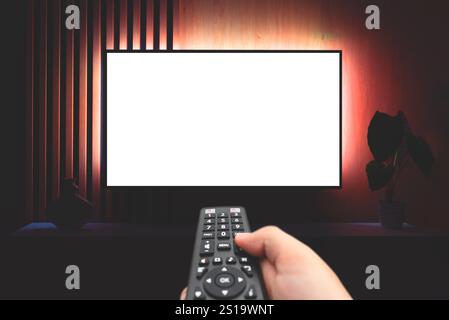 Moderne Wohnzimmereinrichtung mit leerem Smart-TV. TV-Konzept, Fernbedienung in der Hand Stockfoto