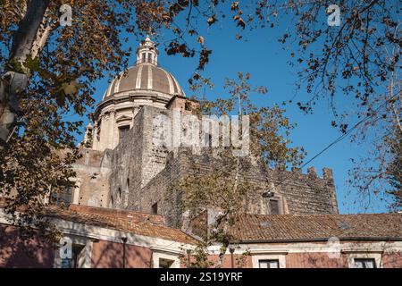 Historischer Blick auf die Mauern von Carlo V, Teil der Befestigungsanlagen von Catania aus dem 16. Jahrhundert, mit der Kuppel der barocken Badia di Sant’Agata im Hintergrund. Stockfoto