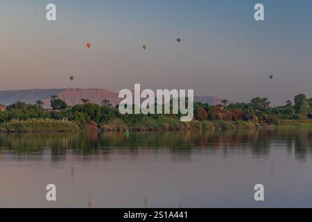 Ein faszinierender Blick auf lebendige Heißluftballons, die bei Sonnenaufgang über Luxor, Ägypten, schweben Stockfoto