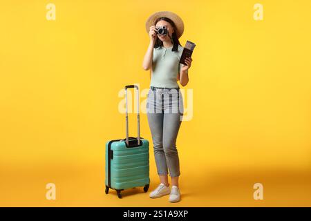 Frau mit Tickets, Pass, Koffer und Vintage-Kamera auf orangem Hintergrund Stockfoto