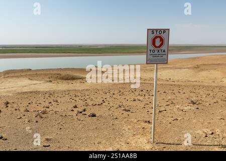 Xorazm Region, Usbekistan - 08. August 2024: Grenze zwischen Usbekistan und Turkmenistan in der Nähe des Flusses Amu Darya mit einem Warnschild Stockfoto