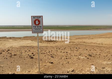 Xorazm Region, Usbekistan - 08. August 2024: Grenze zwischen Usbekistan und Turkmenistan in der Nähe des Flusses Amu Darya mit einem Warnschild Stockfoto