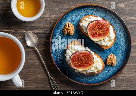 Zwei Sandwiches mit frischen Feigenscheiben, weißem Hüttenkäse, Honig und Walnüssen auf Toastbrot auf einem Teller, Blick von oben, Nahaufnahme. Gesunde Ernährung. Köstlich Stockfoto