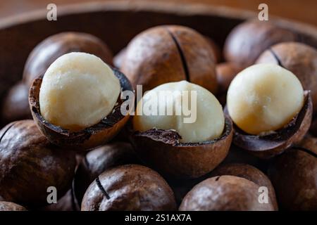 Macadamia-Nüsse mit Schalen in Holzschale, Nahaufnahme Stockfoto