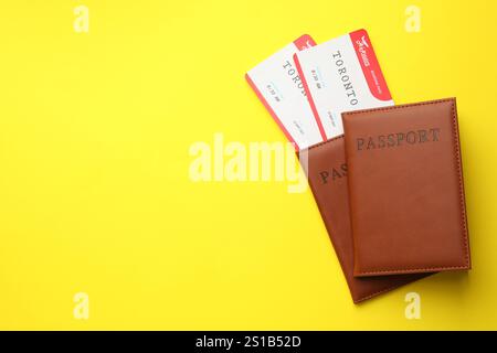 Reisebüro. Flugtickets und Pässe auf gelbem Hintergrund, Blick von oben. Leerzeichen für Text Stockfoto