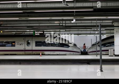 Barcelona, Spanien - 21. Dezember 2024: Hochgeschwindigkeitszüge am Bahnhof Barcelona Sants mit schlanken AVE-Zügen und einem Alleinreisenden auf dem Bahnsteig Stockfoto