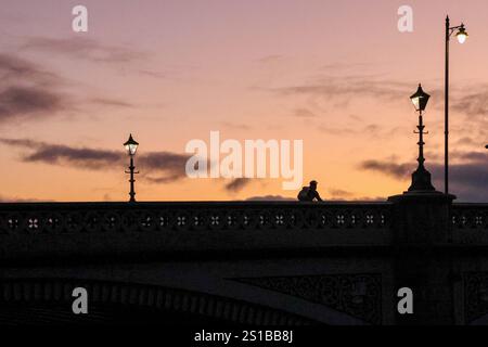 Albert Bridge, Belfast, Nordirland, Großbritannien. Januar 2025. Wetter in Großbritannien – eine weitere kalte Nacht vor uns, die Temperaturen schweben um den Gefrierpunkt, während der Himmel sich auflöst und in ganz Nordirland eine Eiswarnung herrscht. Ein Radfahrer radelt an einem Winterabend im Januar über die Albert Bridge nach Hause. Quelle: CAZIMB/Alamy Live News. Stockfoto