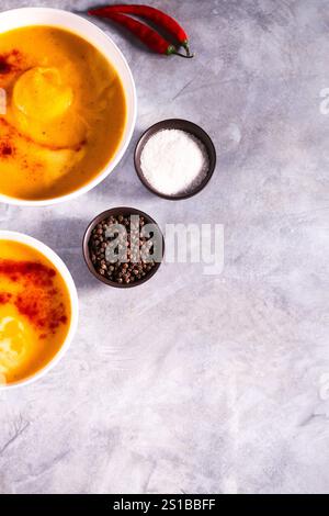 Zwei Schüsseln mit Kürbissuppe mit Chili-Pfeffer und Creme auf weißem Tisch. Flache Ladefläche mit Kopierraum. Cremesuppe. Konzept der leckeren gesunden Ernährung. Stockfoto