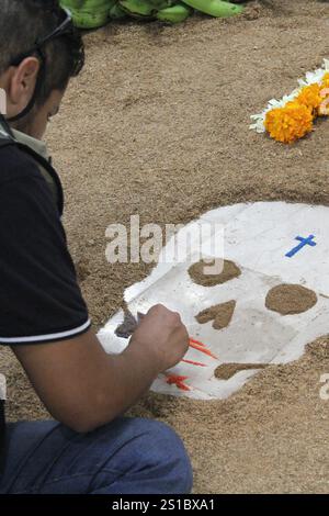 Der Mann gibt handgemachte Day of the Dead Opfergabe mit Schädeln, Cempasuchil-Blumen und Papel Picado, mexikanische Tradition Stockfoto