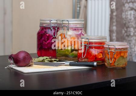 Hausgemachtes gesundes eingelegtes Gemüse in Glasgläsern. Eine Auswahl an farbenfrohen, leckeren Gemüse, das als veganes oder als Beilage genossen werden kann. Stockfoto