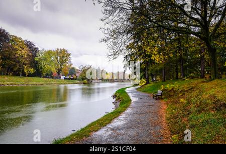 Schlängelnder Pfad am See mit gefallenen Blättern im Washington Park an einem nebeligen Herbsttag in Albany, New York. Stockfoto