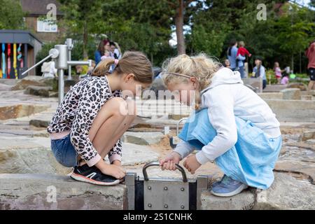 Zwei Schwestern, 8 und 7, spielen mit einem Wasserspiel auf einem Spielplatz in Brent Cross Town, einem Bauprojekt in NW London Stockfoto