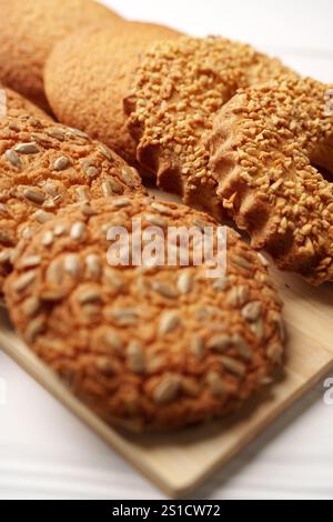 Verschiedene Kekse mit Sonnenblumenkernen und knusprigen Belägen auf einer Holzplatte Stockfoto