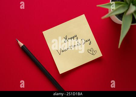 Happy Valentine's Day geschrieben auf einer gelben Karte auf rotem Hintergrund Stockfoto