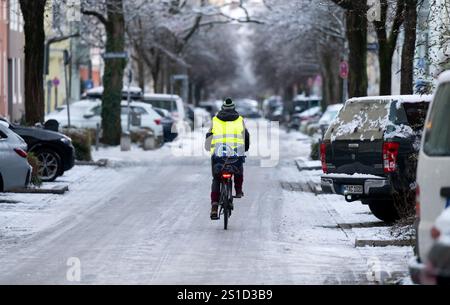 München, Deutschland. Januar 2025. Ein Mann fährt mit dem Fahrrad über eine schneebedeckte Straße im Stadtzentrum. Quelle: Sven Hoppe/dpa/Alamy Live News Stockfoto