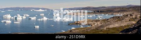Eine atemberaubende Küstenlandschaft in der Nähe von Ilulissat, Grönland, mit dem Arktischen Ozean, der von riesigen Eisbergen gesäumt ist. Die zerklüftete Küste und das eisige Wasser Stockfoto