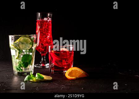 Sommergetränk auf schwarzem Hintergrund. Negroni, Mojito und Aperol. Klassisches erfrischendes Getränk auf schwarzem Hintergrund. Stockfoto