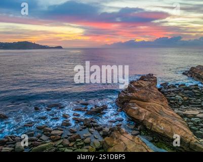 Das Zusammenspiel von Nebel und hohen Wolken verleiht dieser Küstensonnenaufgangsszene am Avoca Beach an der Central Coast von New South Wales, Au, eine zauberhafte Note Stockfoto