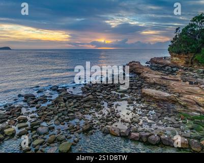 Das Zusammenspiel von Nebel und hohen Wolken verleiht dieser Küstensonnenaufgangsszene am Avoca Beach an der Central Coast von New South Wales, Au, eine zauberhafte Note Stockfoto