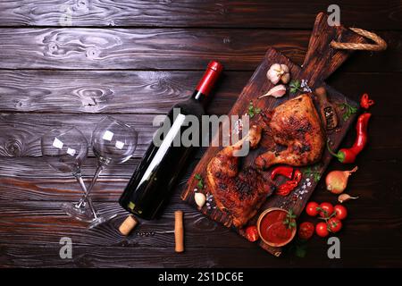 Gegrillte Hähnchenkeulen mit Gewürzen und Gemüse, dazu eine Flasche Rotwein. Stockfoto