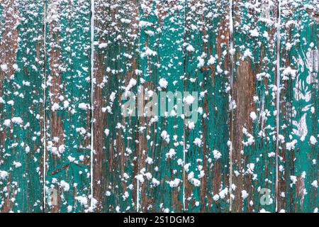 Verschlechterung grüner Holzzaun mit Schnee - rustikale Winterhintergrundstruktur Stockfoto