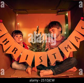 2 Kinder vermitteln einen herzerwärmenden, innovativen Ansatz bei Feiertagen und betonen, dass der wahre Geist von Weihnachten in gemeinsamen Momenten liegt Stockfoto