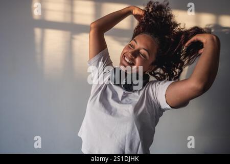 Eine entspannte junge Frau streckt bei Sonnenuntergang den Arm im Wohnzimmer Stockfoto