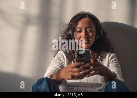 Junge Frau, die Kopfhörer hört und ein Smartphone ansieht Stockfoto