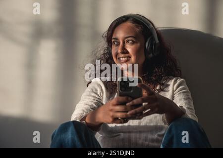 Junge Frau, die Kopfhörer hört und den Sonnenuntergang genießt Stockfoto