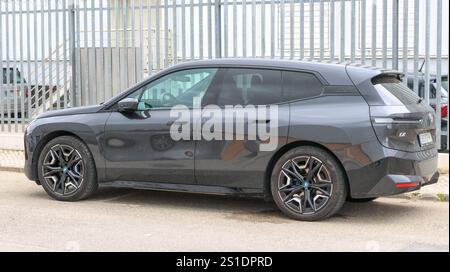 Der moderne elektrische bmw ix suv parkt auf einer Straße in der Nähe eines Metallzauns Stockfoto