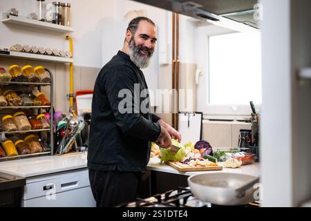 Der professionelle Koch bereitet in der Küche des Restaurants eine Mahlzeit zu. Er macht ein vegetarisches Mittagessen. Stockfoto