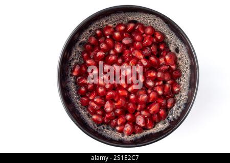 Nahaufnahme einer grauen und weißen Tonschale, gefüllt mit roten dreieckigen Granatapfelkernen auf weißem Hintergrund Stockfoto