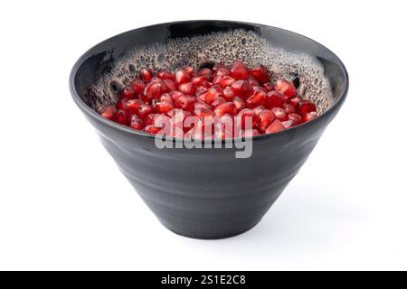 Nahaufnahme einer grauen und weißen Tonschale, gefüllt mit roten dreieckigen Granatapfelkernen auf weißem Hintergrund Stockfoto