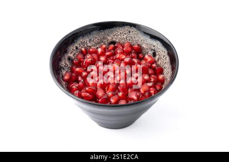 Nahaufnahme einer grauen und weißen Tonschale, gefüllt mit roten dreieckigen Granatapfelkernen auf weißem Hintergrund Stockfoto