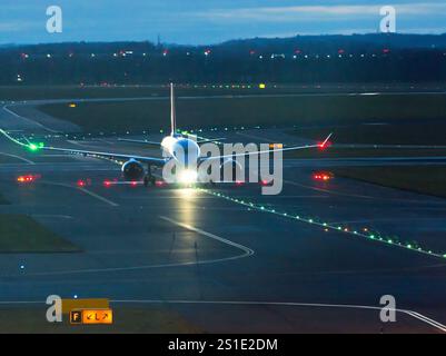 Gewerbliche Jet-Flugzeuge auf der Landebahn mit Licht, nähern sich dem Terminal nach der Landung in der Dämmerung Stockfoto