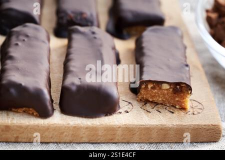 Hausgemachte gesunde Riegel aus Molkenproteinpulver und Erdnussbutter in Schokolade überzogen, Nahaufnahme Stockfoto