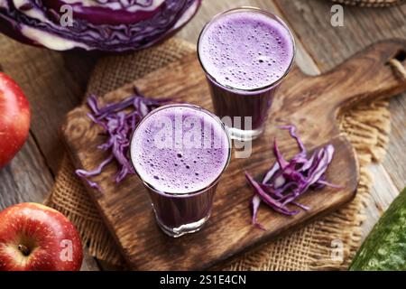 Purpurkohl-Saft mit roten Äpfeln und Gurke auf einem Tisch Stockfoto