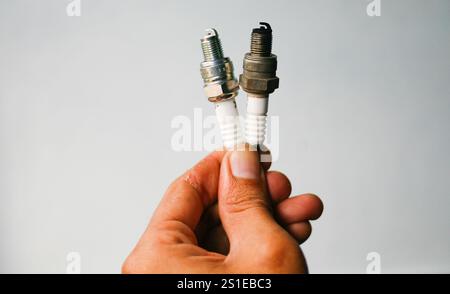 Nahaufnahme der Hand, die den alten und neuen Zündkerzenmotor hält Stockfoto