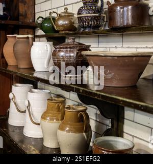 Sammlung von viktorianischen Küchenkrügen und Schüsseln auf Regalen mit weißen Fliesenwänden Stockfoto