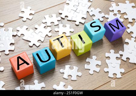 Wort Autismus aus bunten Würfeln und Puzzleteilen aus hölzernem Hintergrund Stockfoto