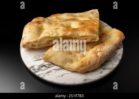 Fladenbrotscheiben auf weißer Marmorplatte auf schwarzem Hintergrund Stockfoto