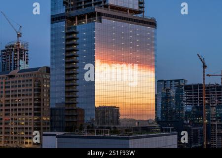 Sonnenuntergangswolken spiegeln sich in Glasfenstern im Büro- und Wohngebäude von Sixth und guadalupe Street in Austin Texas Stockfoto