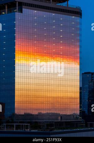 Sonnenuntergangswolken spiegeln sich in Glasfenstern im Büro- und Wohngebäude von Sixth und guadalupe Street in Austin Texas Stockfoto