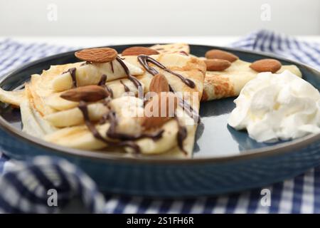 Leckere Crepes mit Schokoladensoße, Mandeln und Schlagsahne auf dem Tisch, Nahaufnahme Stockfoto