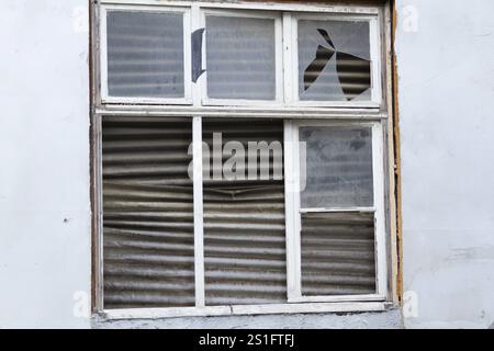 Altes verfallenes Fenster, das von innen mit Wellpappe bedeckt ist Stockfoto