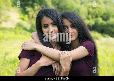 Erwachsene weibliche Zwillinge, die sich umarmen - Außenaufnahme Stockfoto