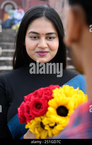 Eine junge indische Frau, die am Valentinstag einen bunten Blumenstrauß aus Sonnenblumen und Rosen erhält, fühlt sich fröhlich und geliebt, während sie Zeit miteinander verbringt Stockfoto