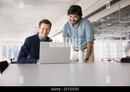 Fröhliche, multiethnische Kollegen sehen sich die Online-Projektpräsentation an Stockfoto