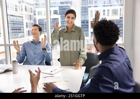 Fröhlich aufgeregte multiethnische Geschäftsfreunde, die die Hände für High Five heben Stockfoto