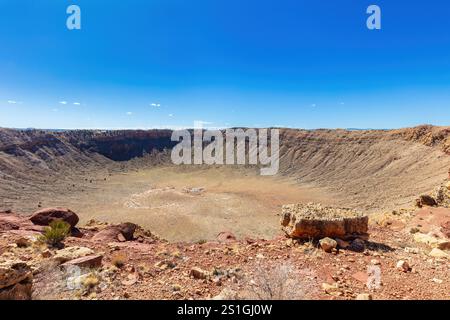 Barringer Meteor-Krater in der Nähe von Winslow, Arizona; Aussichtsplattform sichtbar, zeigt die immense Größe. Verwitterte Felsen, Wüstenpflanzen. Stockfoto